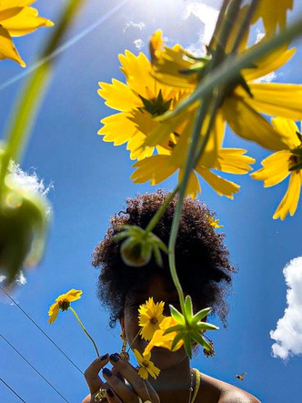 a person with an afro in front of yellow flowers