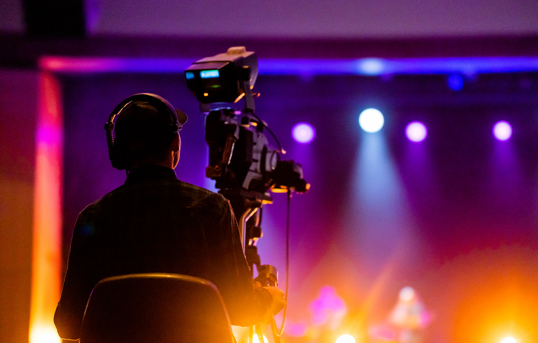 a person standing in front of a stage with a video camera